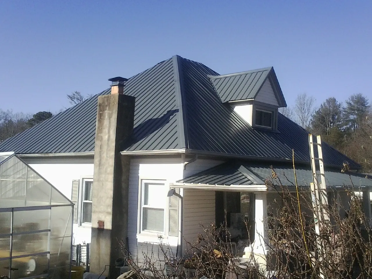 Dark blue standing seam metal roof on a white farmhouse with dormer — Slate & Tile Roof Repair by Roofing Brothers in Arthur