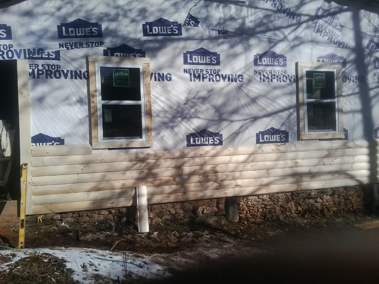 House wrap and new log siding going up on an exterior wall in Arthur