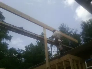 Carpenter setting a ridge beam over a new addition frame — Ice Dam Removal by Roofing Brothers in Arthur