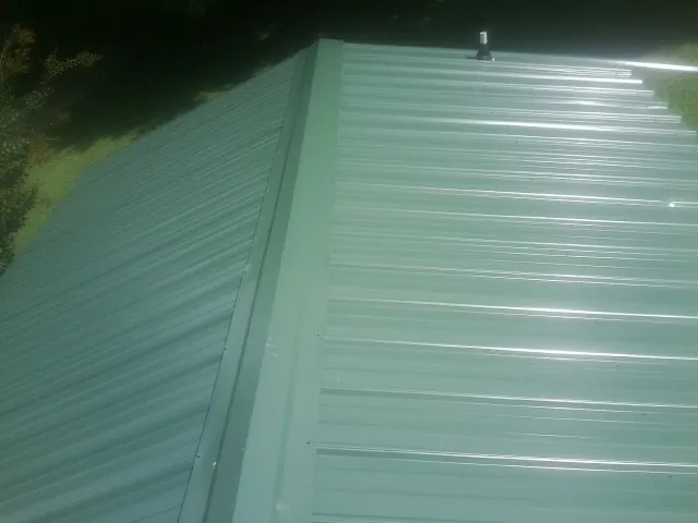 New green metal panels meeting at the ridge of a roof — Flat Roof Repair work by our crew in Arthur