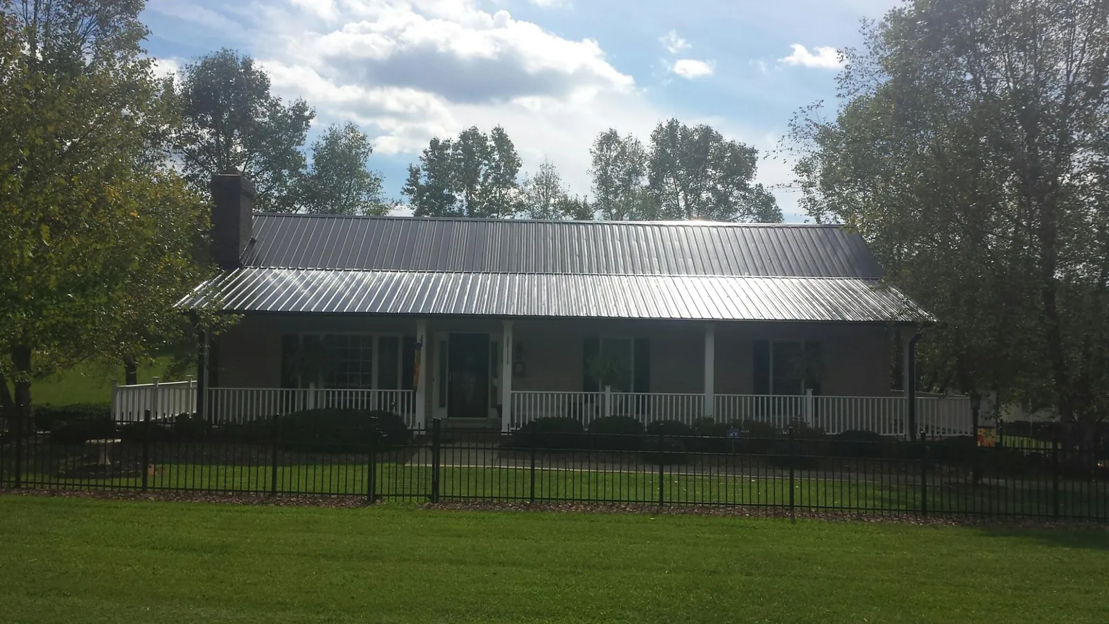 Gray metal roof on a brick ranch with a full width front porch — Gutter Guard Installation work by our crew in Arthur