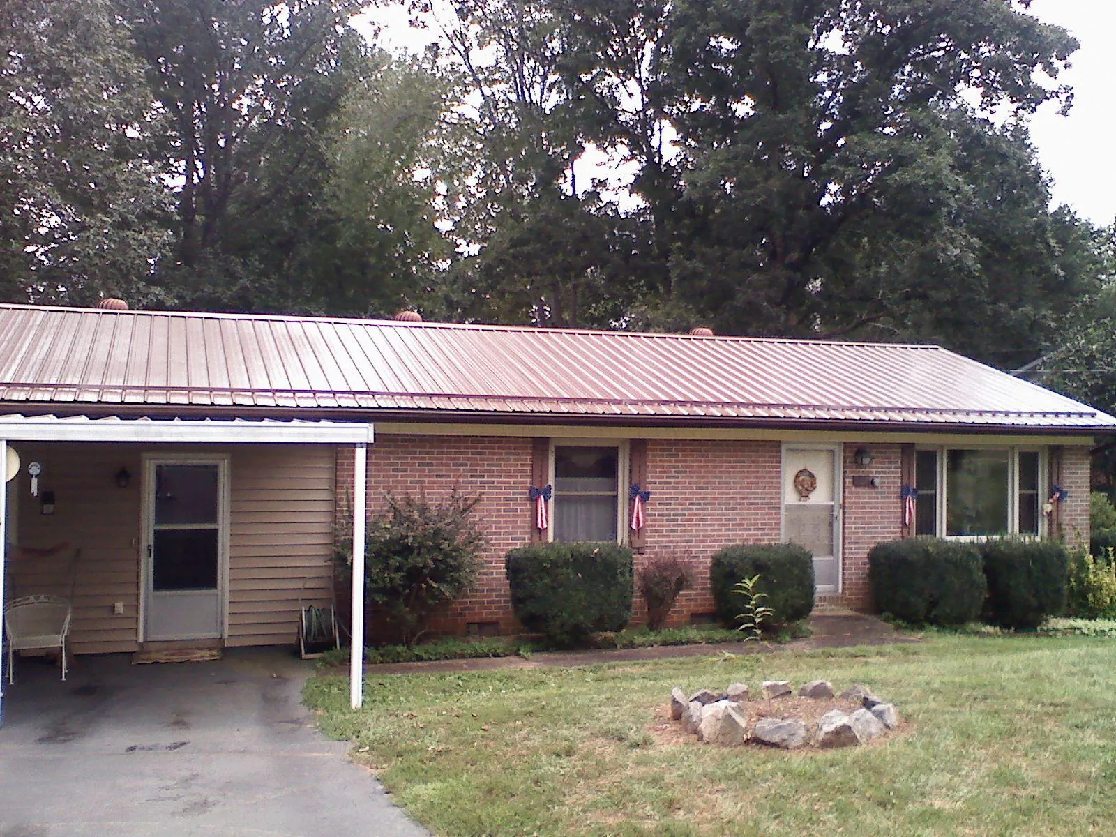 Bronze metal roof and carport on a brick ranch home — Roof Repair work by our crew in Arthur