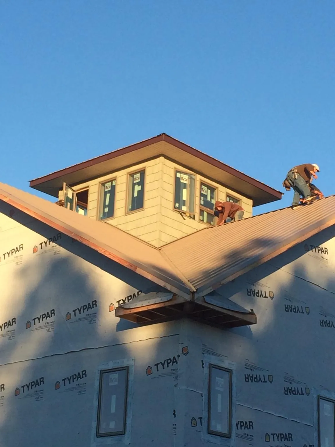Roofers working around a rooftop cupola on a new metal roof at sunset — Roof Waterproofing in Arthur by Roofing Brothers